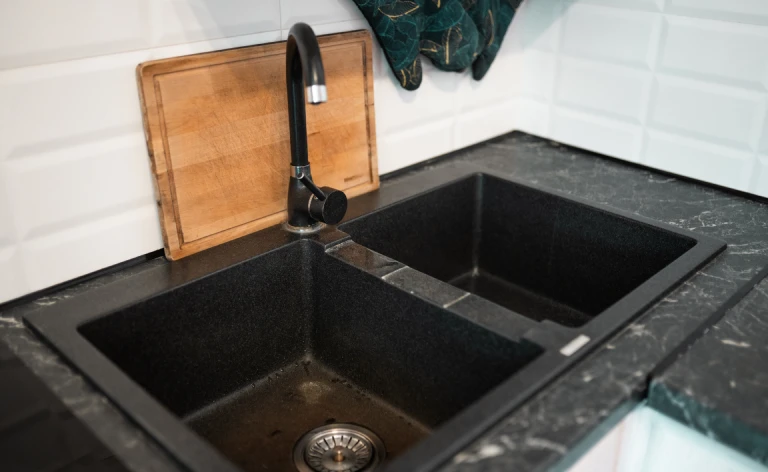 A double-basin sink installed onto a black kitchen countertop