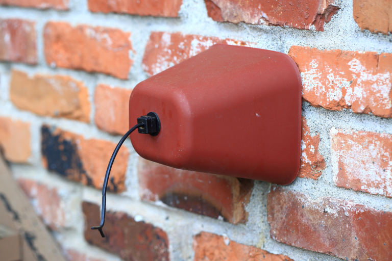 Insulated outdoor faucet cover installed on an exterior brick wall to protect the tap from freezing during winter
