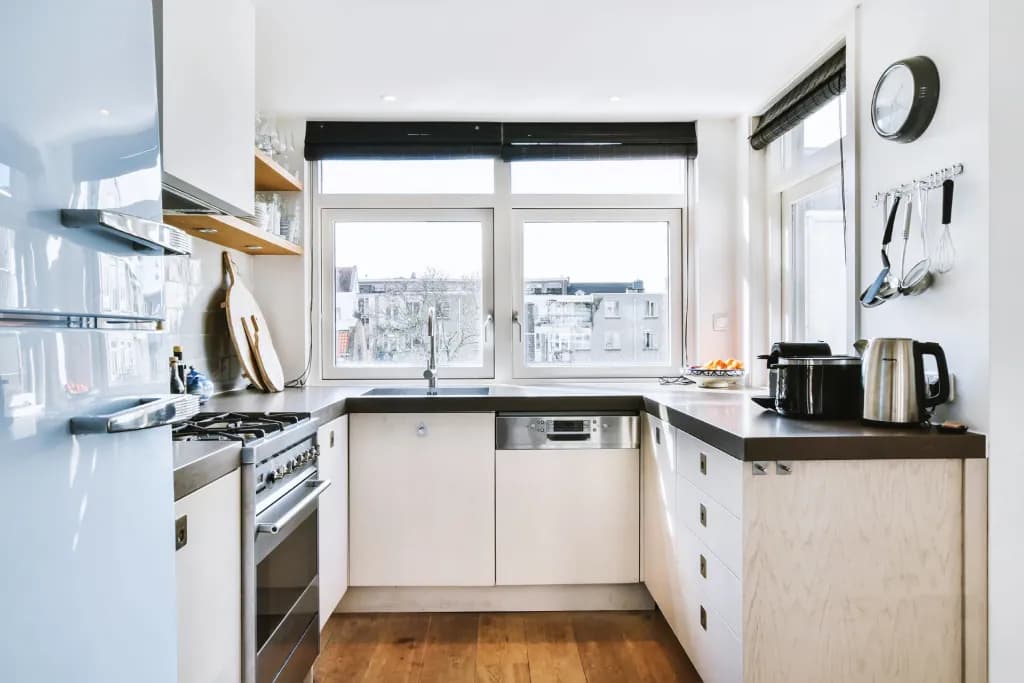 A small kitchen with open shelving, white cabinets, and lots of natural light