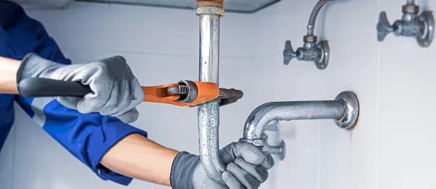 Plumber tightening a drain pipe under a sink in Ancaster