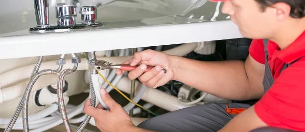 Plumber connecting the water lines under a bathroom sink in Ancaster