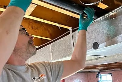 Plumber installing new pipes during a basement renovation