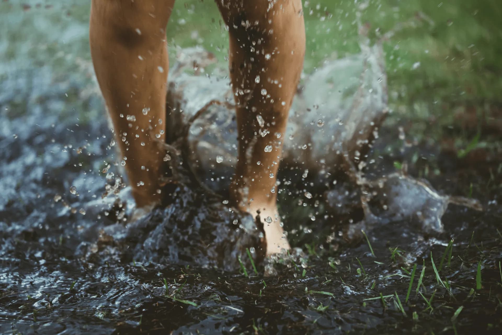 a child jumping in a pool of water in a backyard