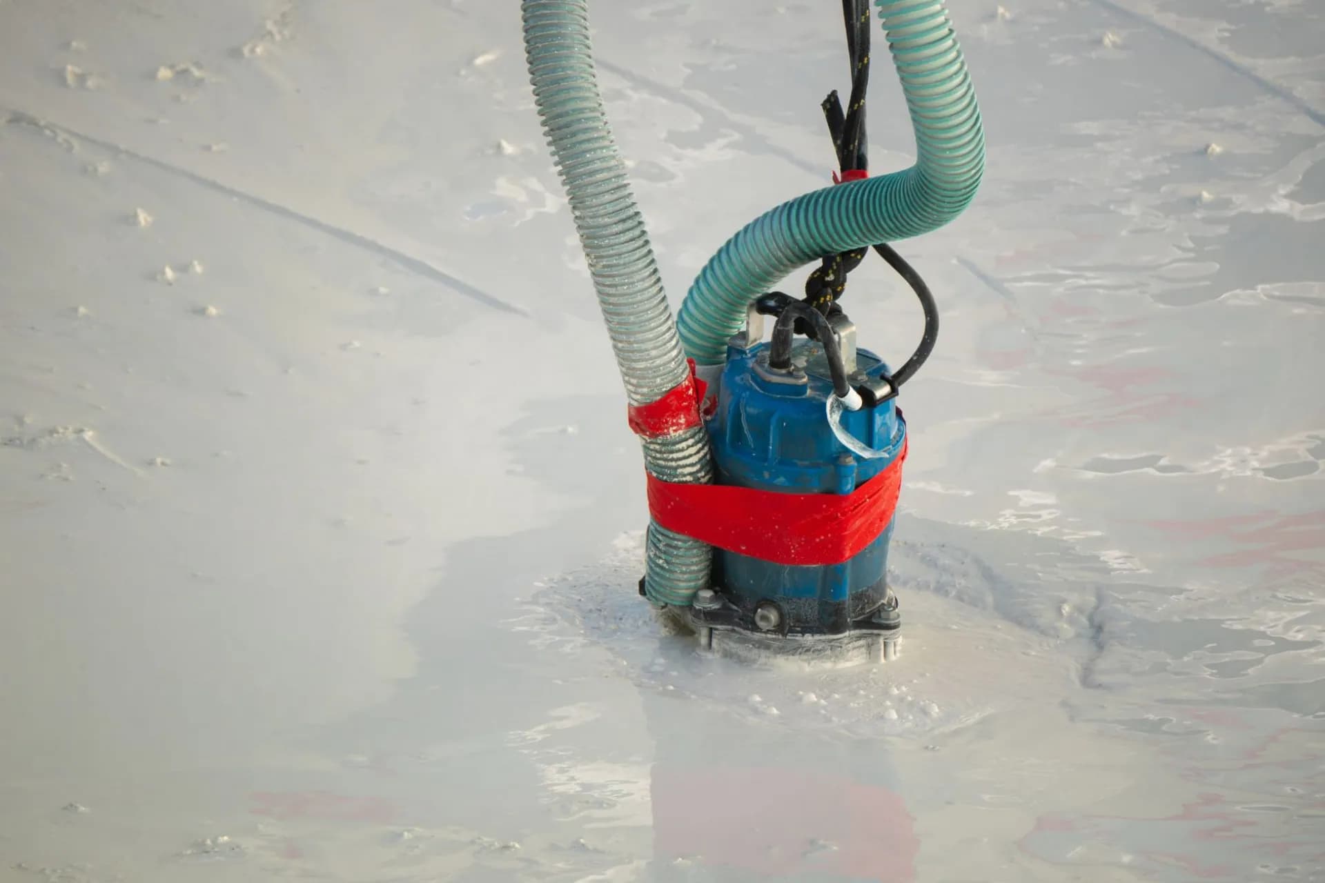 A sump pump in the ground surrounded by water