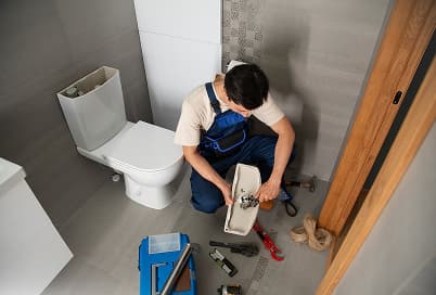 Toilet being repaired by a plumber