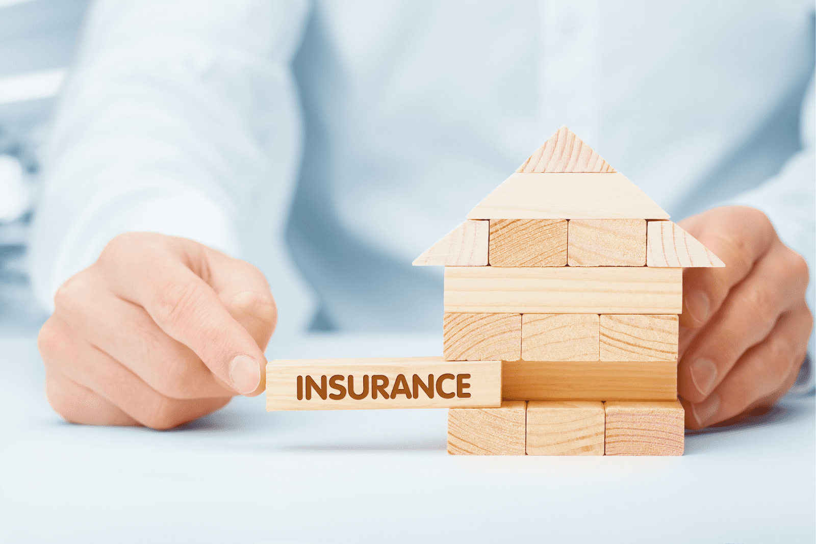 Close up of a small house made of wooden blocks with ‘insurance’ written on one