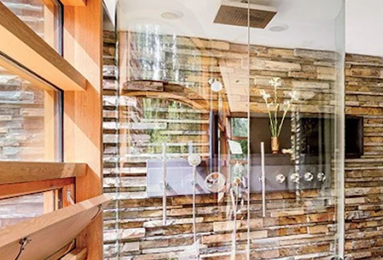 A walk-in curved, glass shower enclosure with jalousie windows