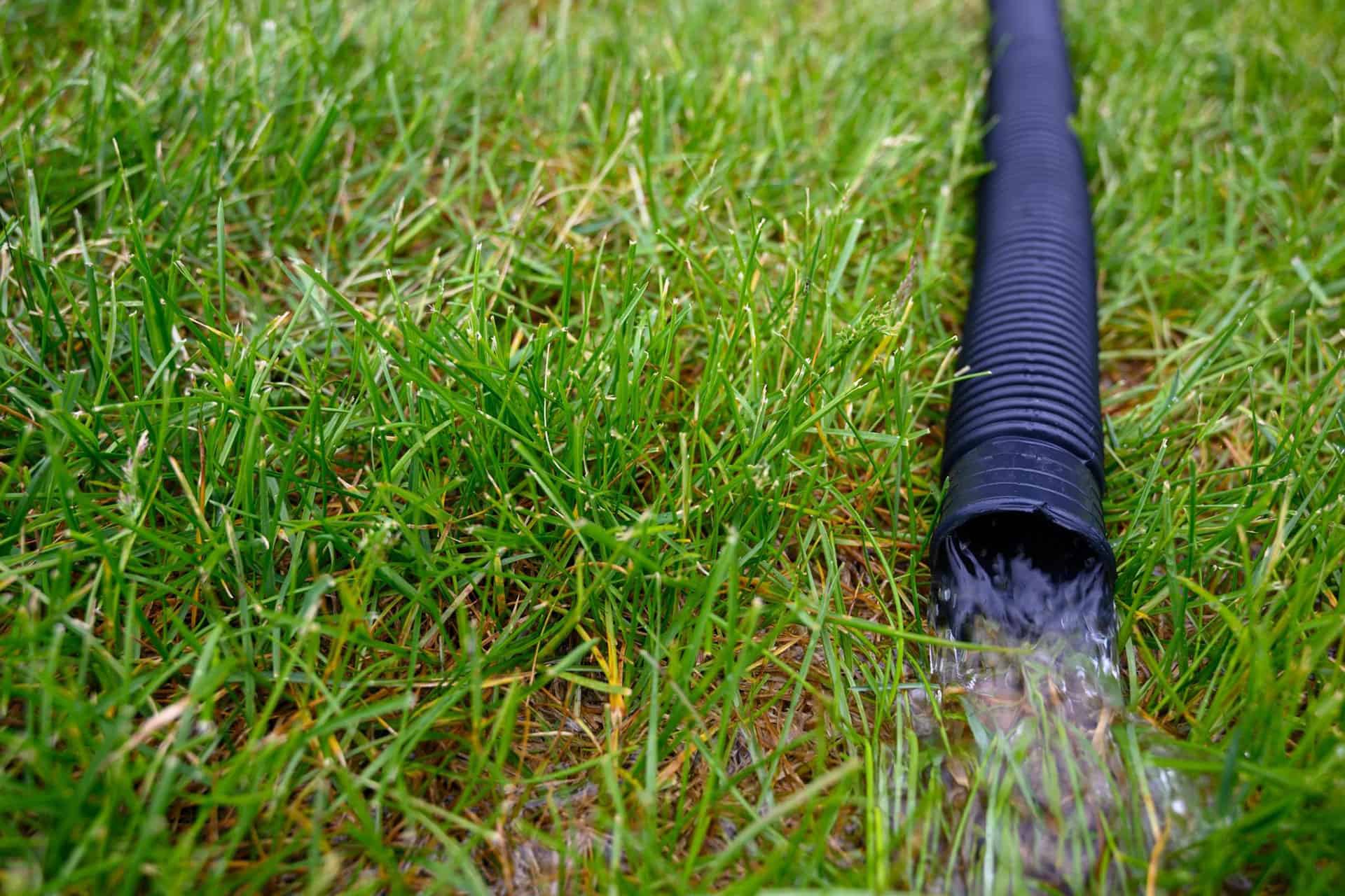 A flexible hose from a residential sump pump carrying water from the flooded basement away from the house