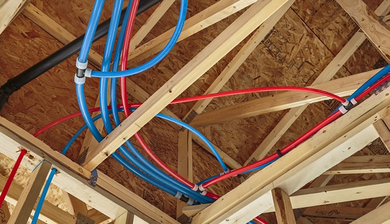 Red and blue pipes installed into a home under construction