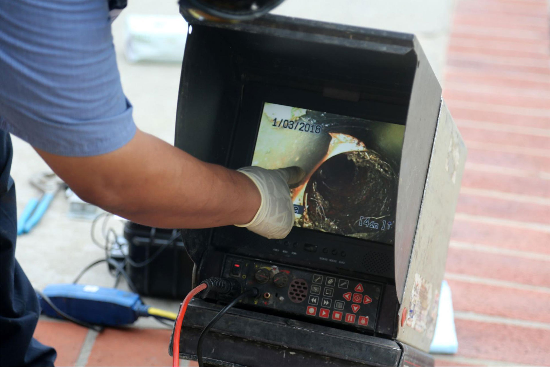A gloved hand cleaning a shower drain