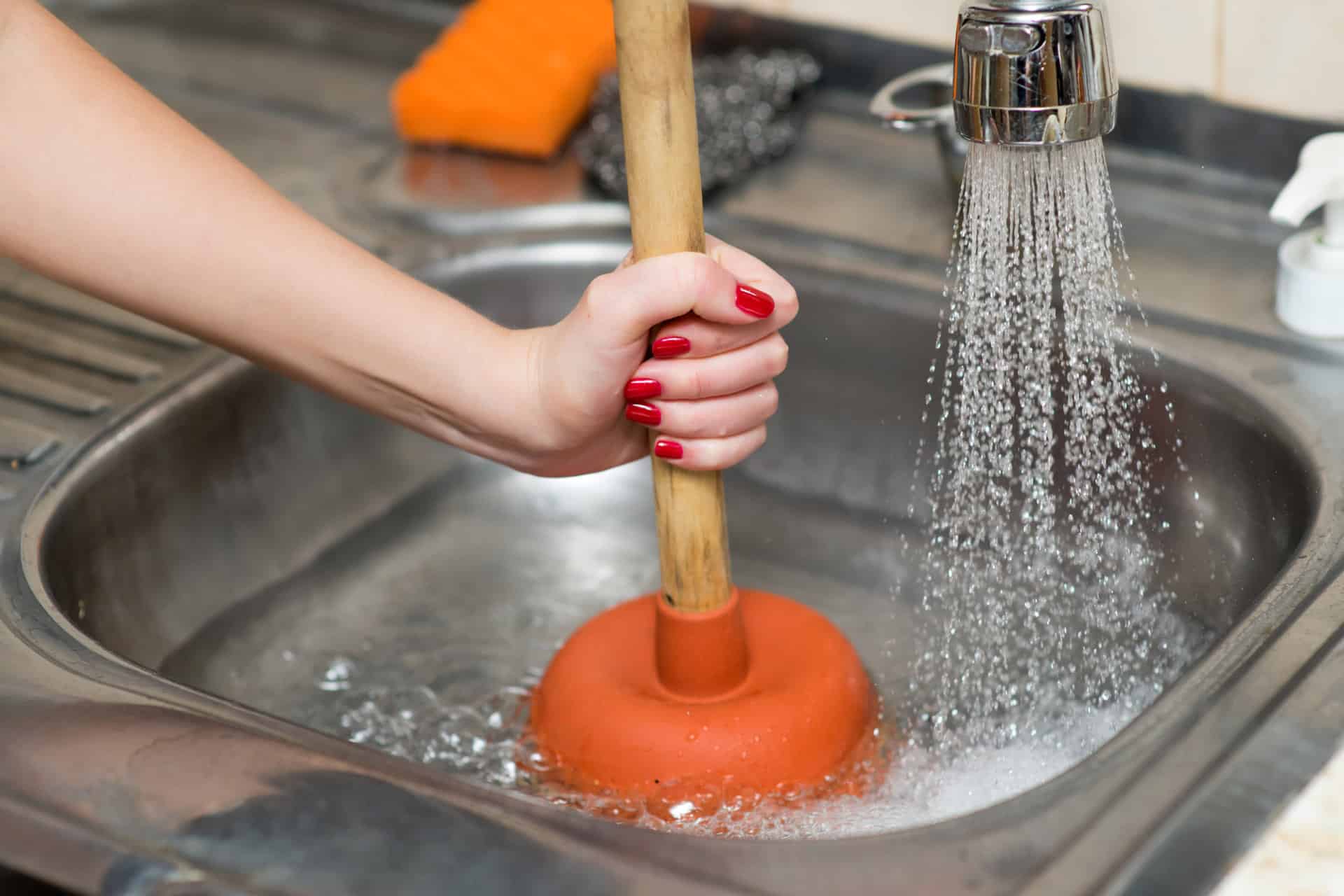 A person unclogging a sink with a plunger
