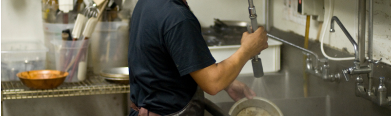 a dishwasher at a restaurant cleans pots and pans