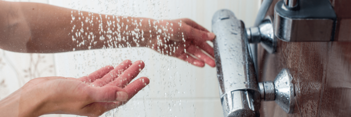 A person testing the temperature of the water in a shower