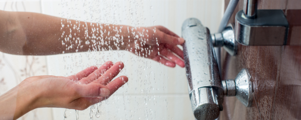 A person testing the temperature of the water in a shower