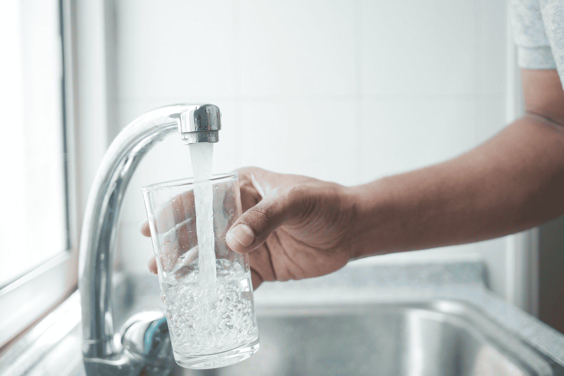 a person fills a glass of water using a touchless faucet

