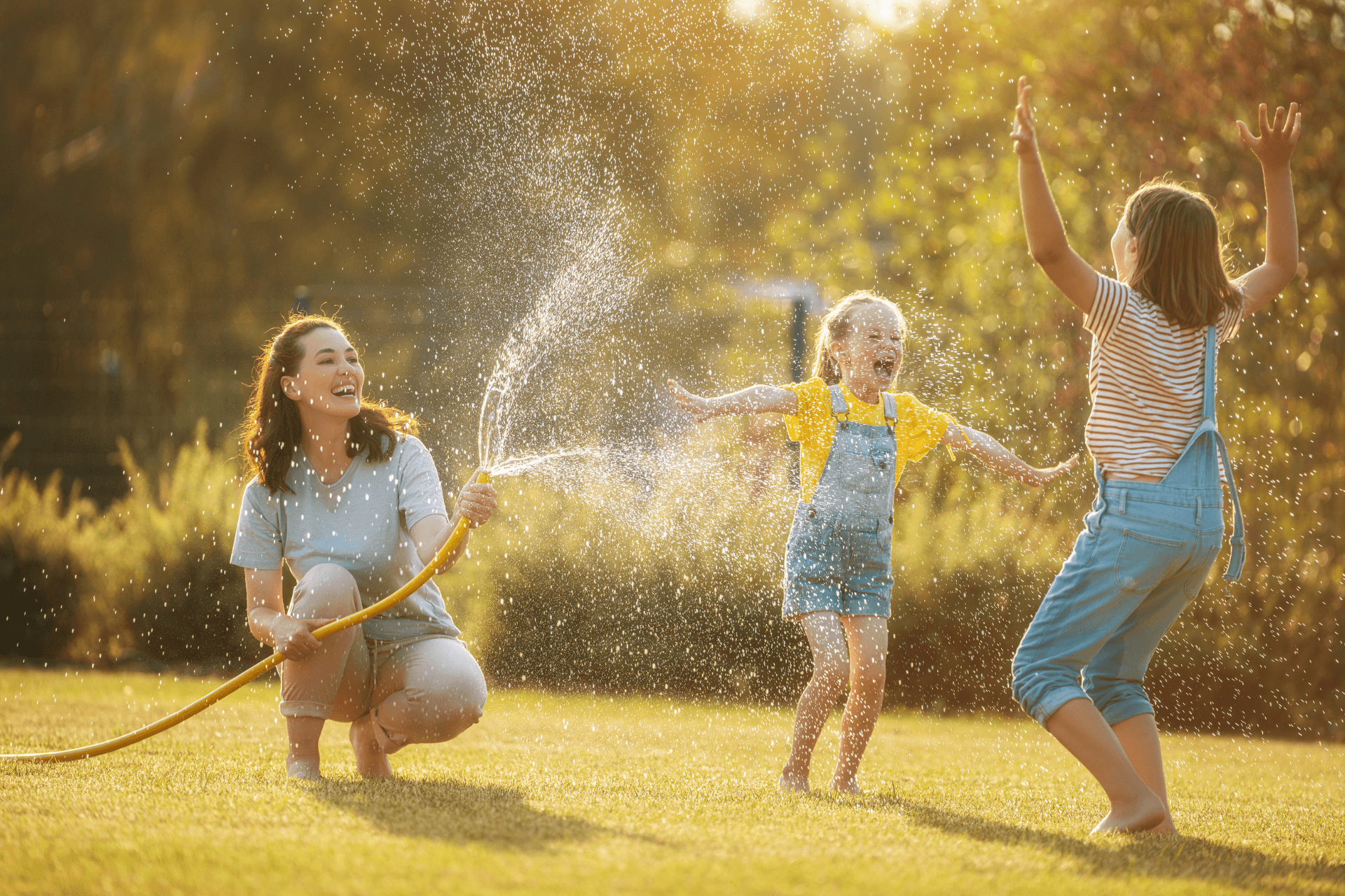 A mom and her two daughters having a water fight 