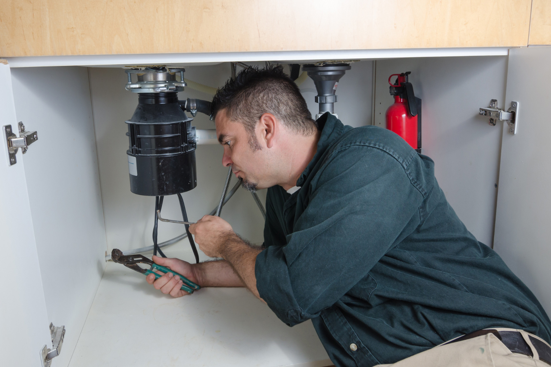A plumber repairing a garbage disposal unit 