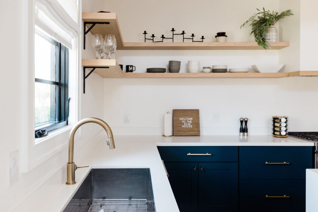 A small kitchen with floating shelves and dark blue cabinets