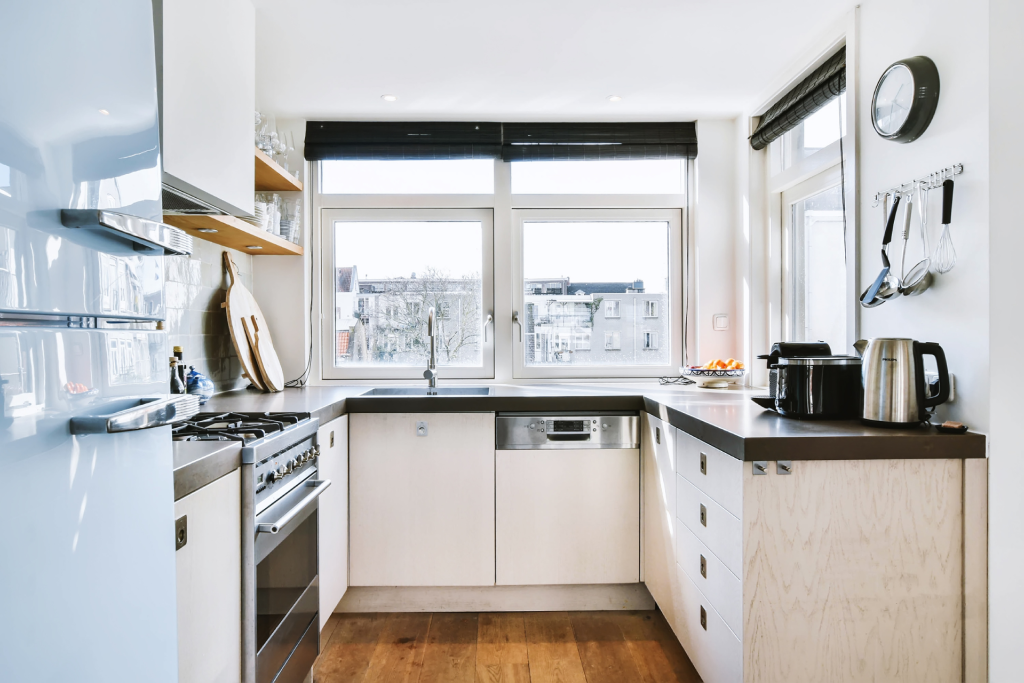 A small kitchen with open shelving, white cabinets, and lots of natural light