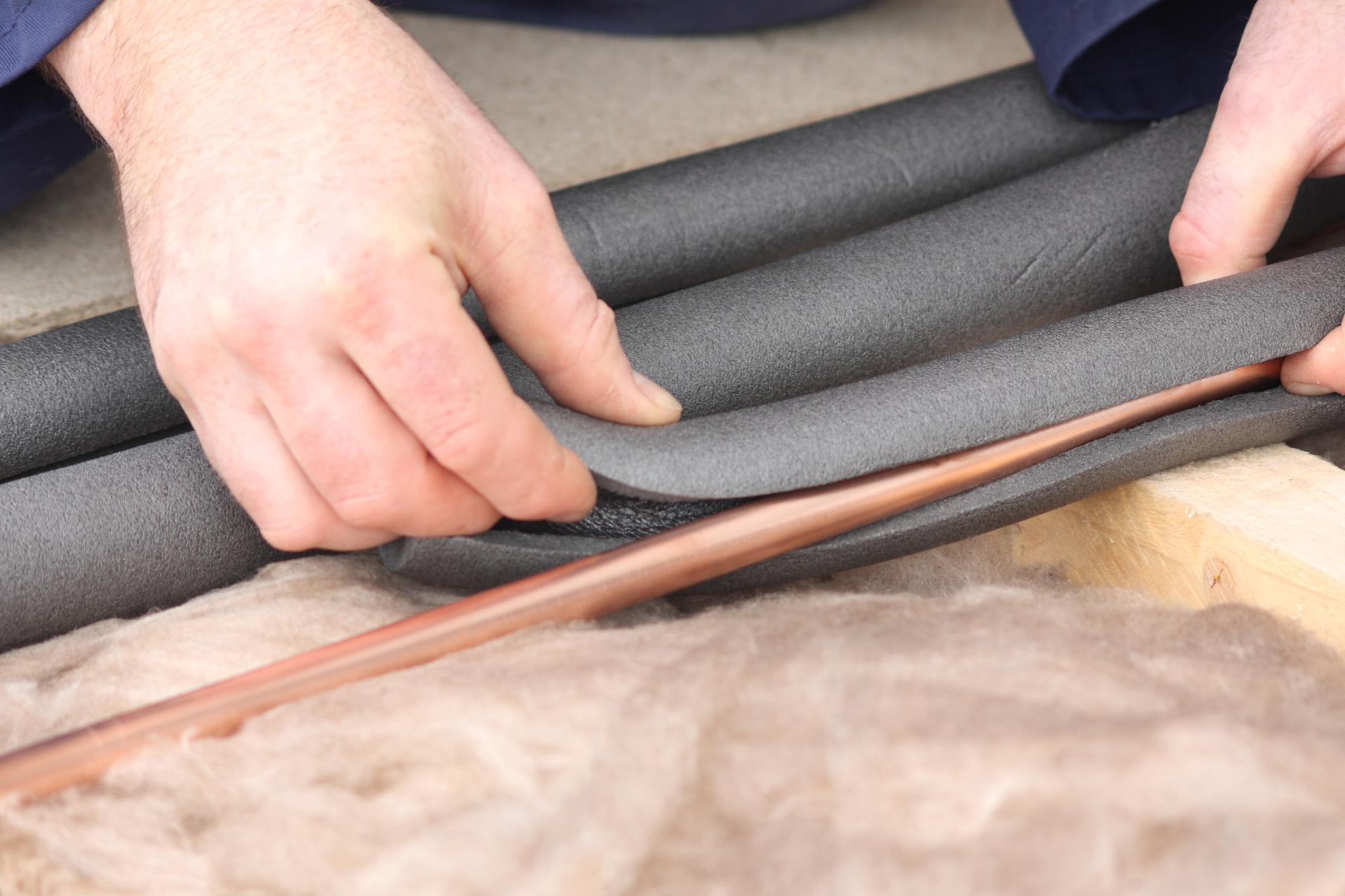  someone applying foam sewer pipe insulation to avoid a frozen septic system 