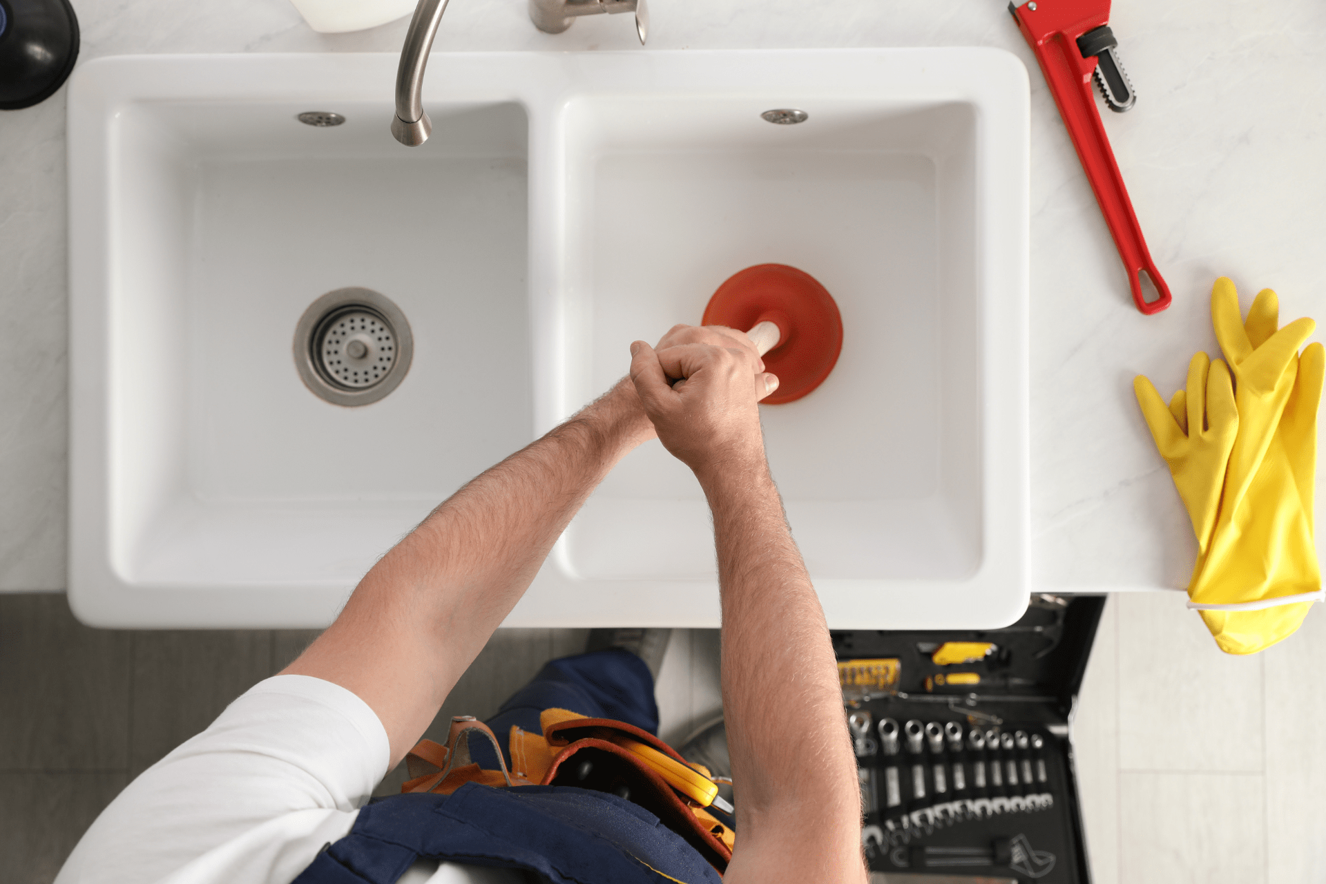 A professional plumber using a plunger on a slow draining bathroom sink