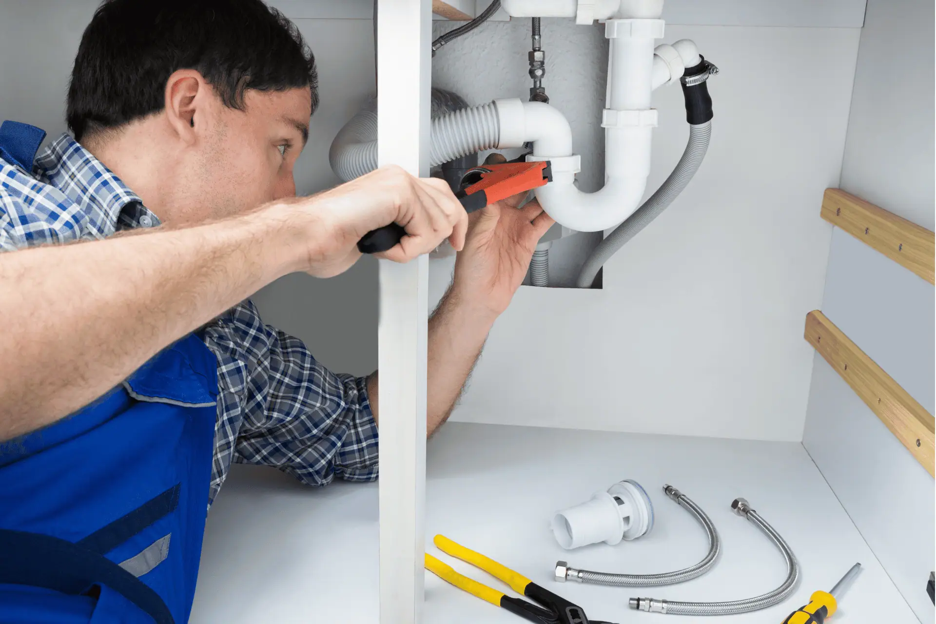 Plumber under a sink, fixing a leaking pipe to fix low water pressure in the home