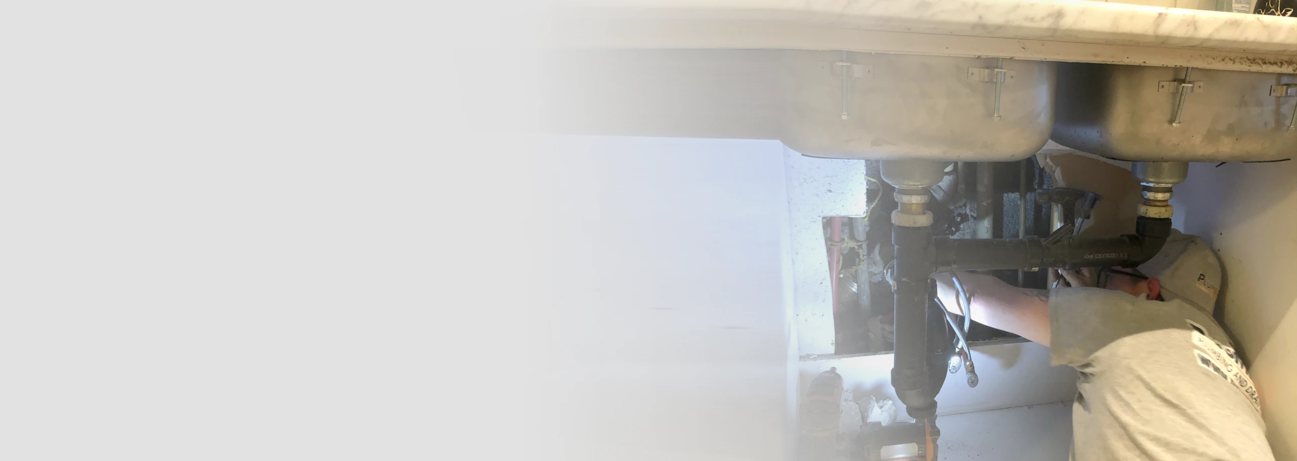 A PlumbWize plumber fixing pipes under the sink